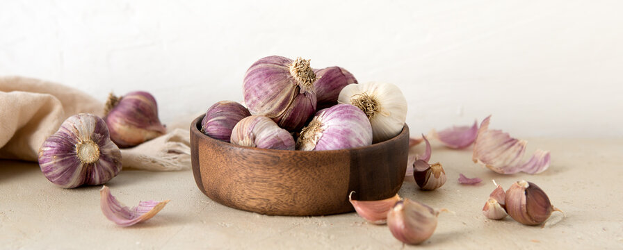 wooden bowl with garlic on a light table