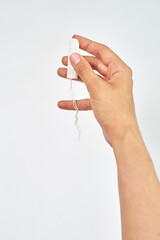 hygienic tampon in a female hand on a white background