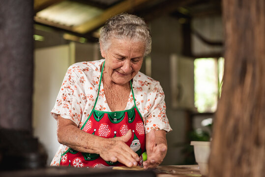 mujer adulta mayor cocinando tortillas de maíz en su estufa de metal  