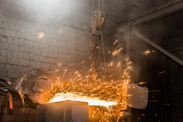 Heavy grinding equipment suspended on a chain with a hook processes and cleans cast iron reinforced concrete tubing in the workshop of an industrial plant