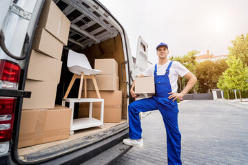 Two removal company workers unloading boxes and furniture from minibus