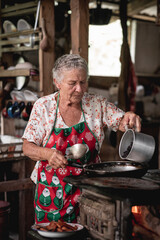 SEÑORA ADULTO MAYOR COCINANDO EN UNA ESTUFA DE METAL ANTIGUA PARA LA CENA DE NAVIDAD