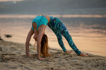 girl on the sunset beach, yoga chakrasana, balance, fitness, stretching and relaxation	