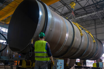 Moving pipes inside the workshop with an overhead crane using a traverse.