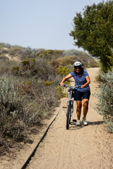 A Beautiful Mature Woman Pushing her Bike through the Sand on a Morro Bay Beach Boardwalk while Exploring the Area