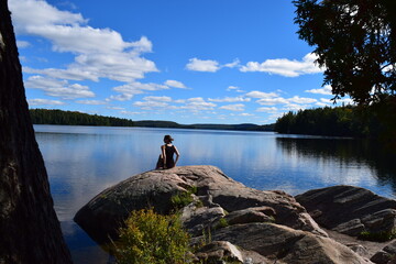 Woman sitting on a rock staring out over a lake in Canada