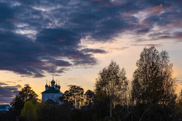 Beautiful evening cloudy sky with church domes and trees.