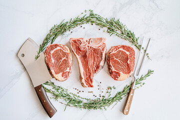 three delicious steaks ready to grill on a white marble surface