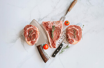three delicious steaks ready to grill on a white marble surface