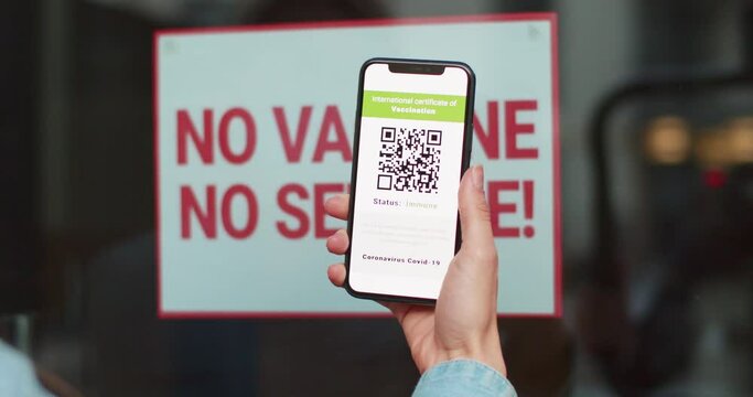 Person using digital health passport app in mobile phone with covid-19 certificate. No vaccine no service. Digital green certificate of immunization with qr code