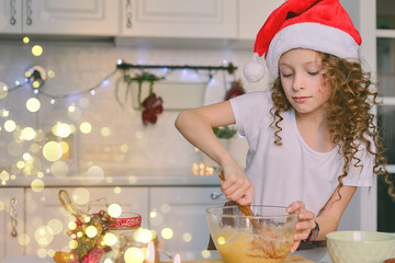 Girl is cooking christmas cookies. She is in the kitchen at home. Horizontal frame. This photo with bokeh.