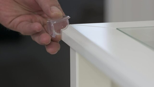 Childproofing a house, child safety devices to protect children at home, baby safety proofing, installing corner guard edge bumper to help prevent injuries from falls against sharp edges of furniture.