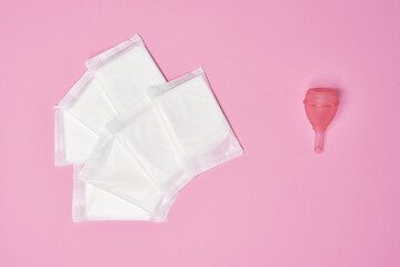 packaged cotton sanitary pad napkin, silicone pink menstrual cup on pink background