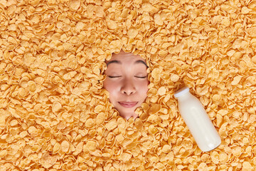 Photo of pleased woman keeps eyes closed imagines how she eats delicious breakfast buried in...