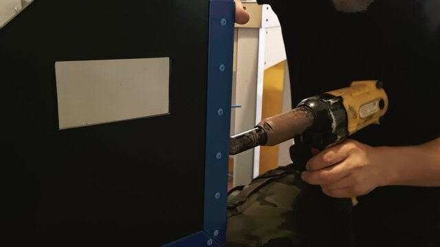 Male mechanic works with pneumatic tool rivet gun. Hands hold electric riveting machine. Blind rivets for metal working. Slow motion.