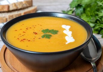 Pumpkin puree soup, garnished with parsley and red pepper.