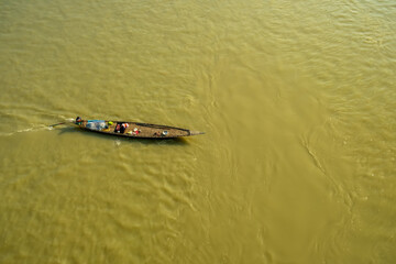 A small fishing boat is sailing on the fast waters of the Ganges River. Water transport.