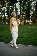 Fototapeta premium Smiling granny holds milk coctail in summer park