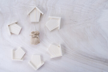 Top view of wooden home arranged in a circle around the money bag put on the white wood in the office, Loan for real estate or saving money for buy a new house to family in the future concept.