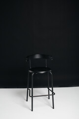 A stylish black chair stands on a black background in the studio room. The concept of a vacancy or an interview. Cinema, director's chair.