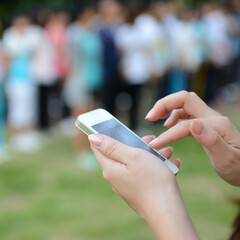 Close up of woman using mobile smart phone in the park.