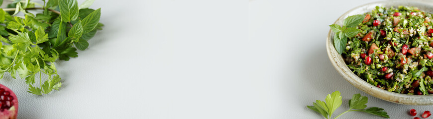 Tabbouleh salad with fresh herbs and pomegranate. Traditional tabouli meal banner background with copy space.