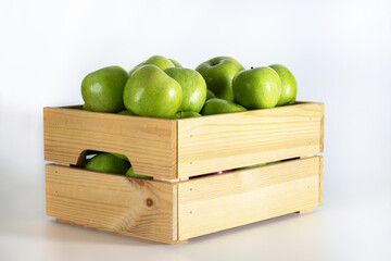 Wooden box of green apples on a white background.