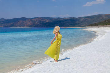 Summer vacations. Lifestyle woman relax and chill on beach background. Caucasian happy young people wearing yellow dress fashion summer trips walking enjoy on sandy tropical beach