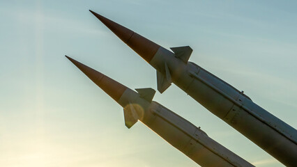 Two combat missiles aimed at the sky. Old ballistic missile launcher on blue sky background.