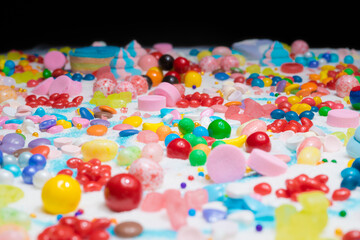 Fototapeta na wymiar Chocolate coated and jelly beans candy mix. Big explosion of variety colour snack and sugar confetti. Festive dessert of different kinds of soft gummy, lollipop for holiday.