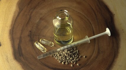 Licensed cannabis CBD oil for medical purposes. Background with small glass jars and syringe, for oral use only. Hydroponic biological seeds and marijuana plant on wood table.