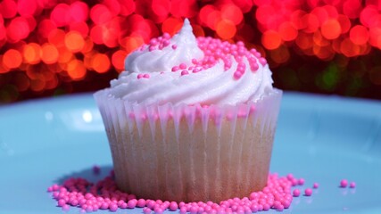 Cupcake macro shallow depth of field and decoration with sugar sprinkles. Cup cake with white vanilla cream on red background. Process of making delicious desserts muffin for birthday or Valentine.