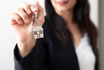 woman's hand handing over house key, home purchase concept.