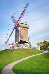 Obraz premium Traditional windmill on rampart Kruisvest in the historic town of Brugge, Belgium. Name of the windmill is Sint-Janshuismolen.