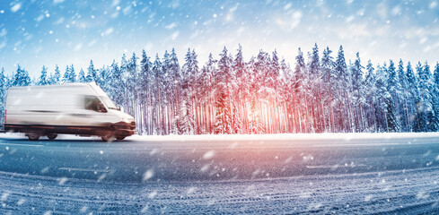 White van moving on a slippery asphalt road in snowfall