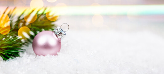Festive New Year web banner with free space for text. Pink Christmas ball on a light background with beautiful bokeh