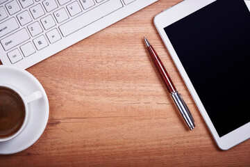 Wooden desk office with pc cayboard, tablet, and other work supplies with cup of coffee. Top view with copy space for input the text. Designer workspace on desk table essential elements on flat la