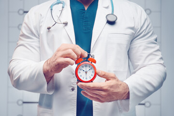 The doctor holds alarm clock in his hands.