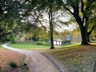 road in the park with lake and old stone bridge
