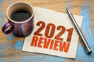 2021 year review text on a napkin with a cup of coffee, end of year business concept