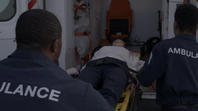 Team of paramedics pulling stretcher with injured woman