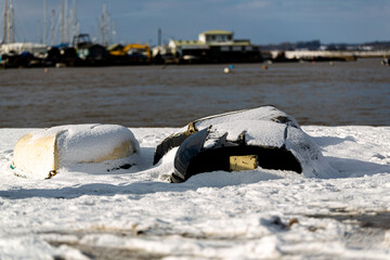 Upturned row boats have been left moored on the beach on the Suffolk coast. They have been covered...