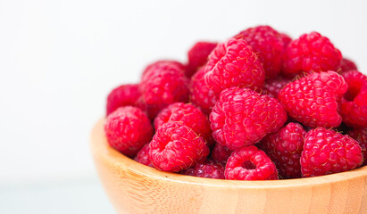 Fresh red raspberry in old wooden plate, copy space