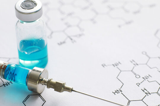 small jars with injection and syringe for injection on a blue background near the chemical formula
