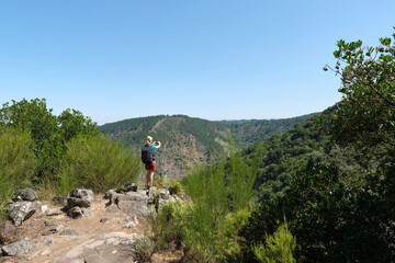 Woman hiker taking a picture of the landscape from a lookout point