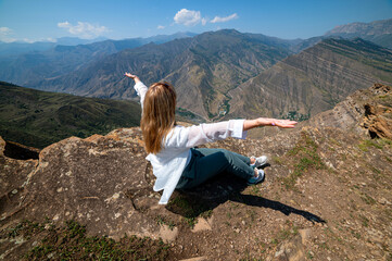 A girl sitting on a rock on a cliff in canyon, Dagestan
