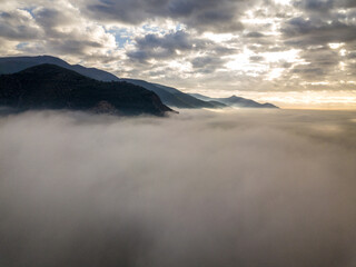 Aerial view of a mountain in the fog at sunrise, Tuscany, Italy.