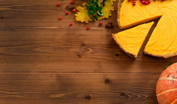 thanksgiving day theme with pumpking pie, yellow leaves and red berries on brown wooden rustic background