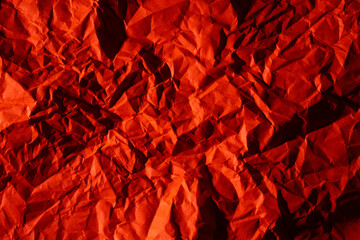 Photo of crumpled wrinkled contrast dark office paper lit with red light, background texture