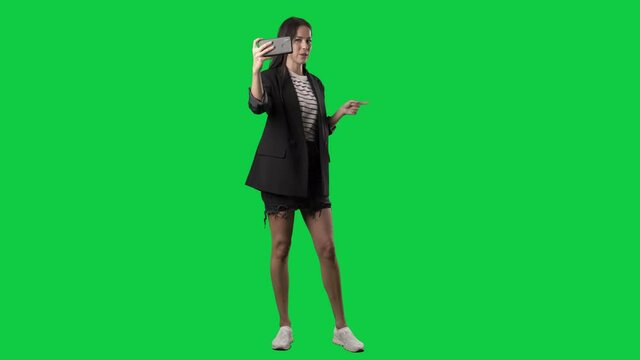 Stylish young woman social media influencer filming selfie video greeting followers. Full body isolated on green screen background
